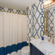 hall bathroom with eclectic wallpaper and white and blue shower curtain