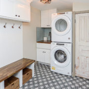 mudroom laundry area with hangers, cabinets, convertible utility sink, and bench with stowaway totes