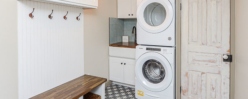 mudroom laundry area with hangers, cabinets, convertible utility sink, and bench with stowaway totes