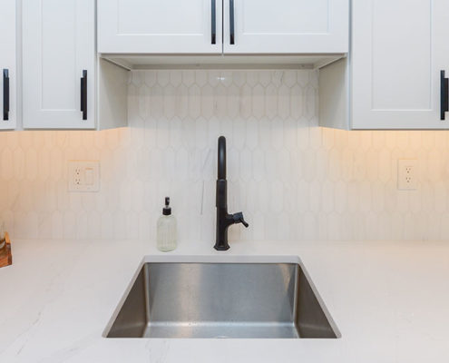 stainless steel sink basin in white kitchen remodel with black hardware