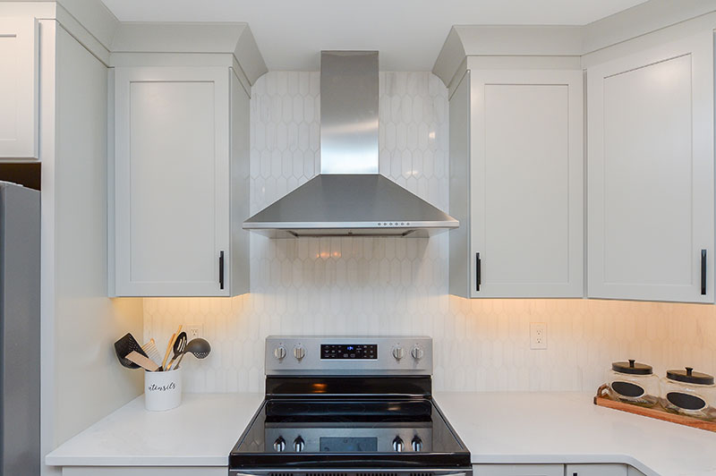 stainless steel range and range hood in white kitchen remodel