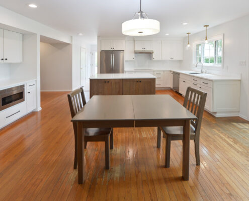 Wooden kitchen table, wooden chairs, fridge, white countertops, window