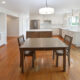 Wooden kitchen table, wooden chairs, fridge, white countertops, window