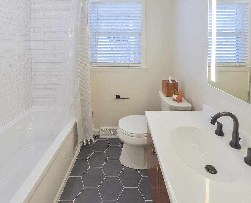 A white bathroom with a gray tile floor and a white vanity