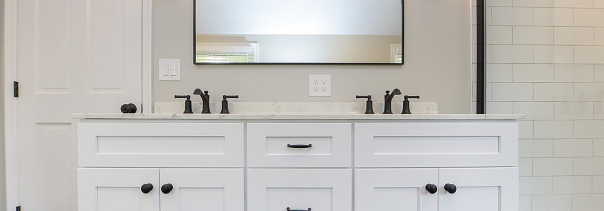 A bathroom with a white double-sink vanity, one mirror, and wall sconce lights