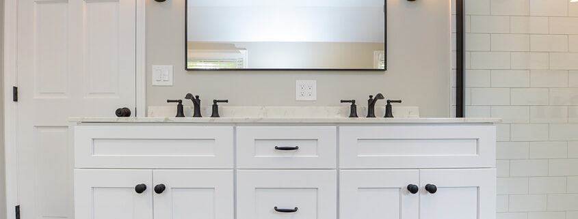 A bathroom with a white double-sink vanity, one mirror, and wall sconce lights