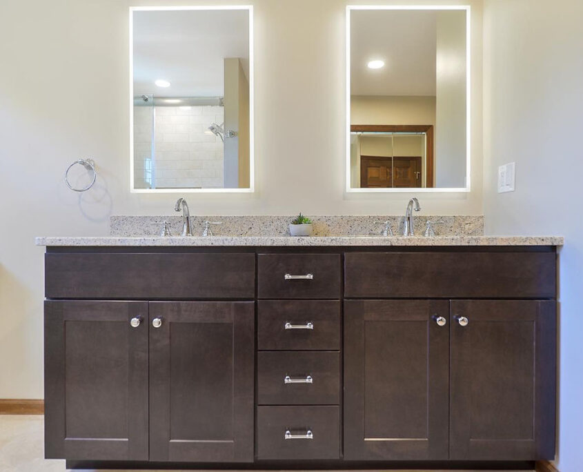 A bathroom vanity made of dark wood, with double sinks and double mirrors 