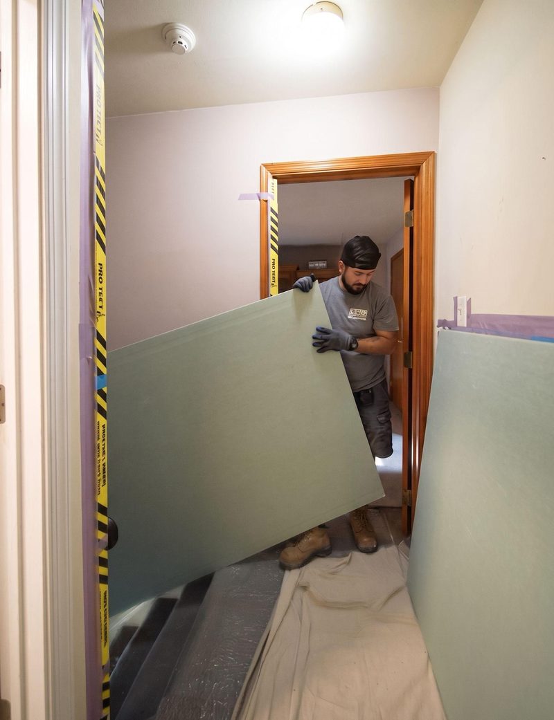 Ayars crew member carrying drywall over protected floors during a remodel