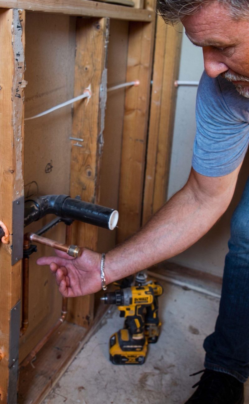 Ayars carpenter checking plumbing rough-in inside an open wall before drywall
